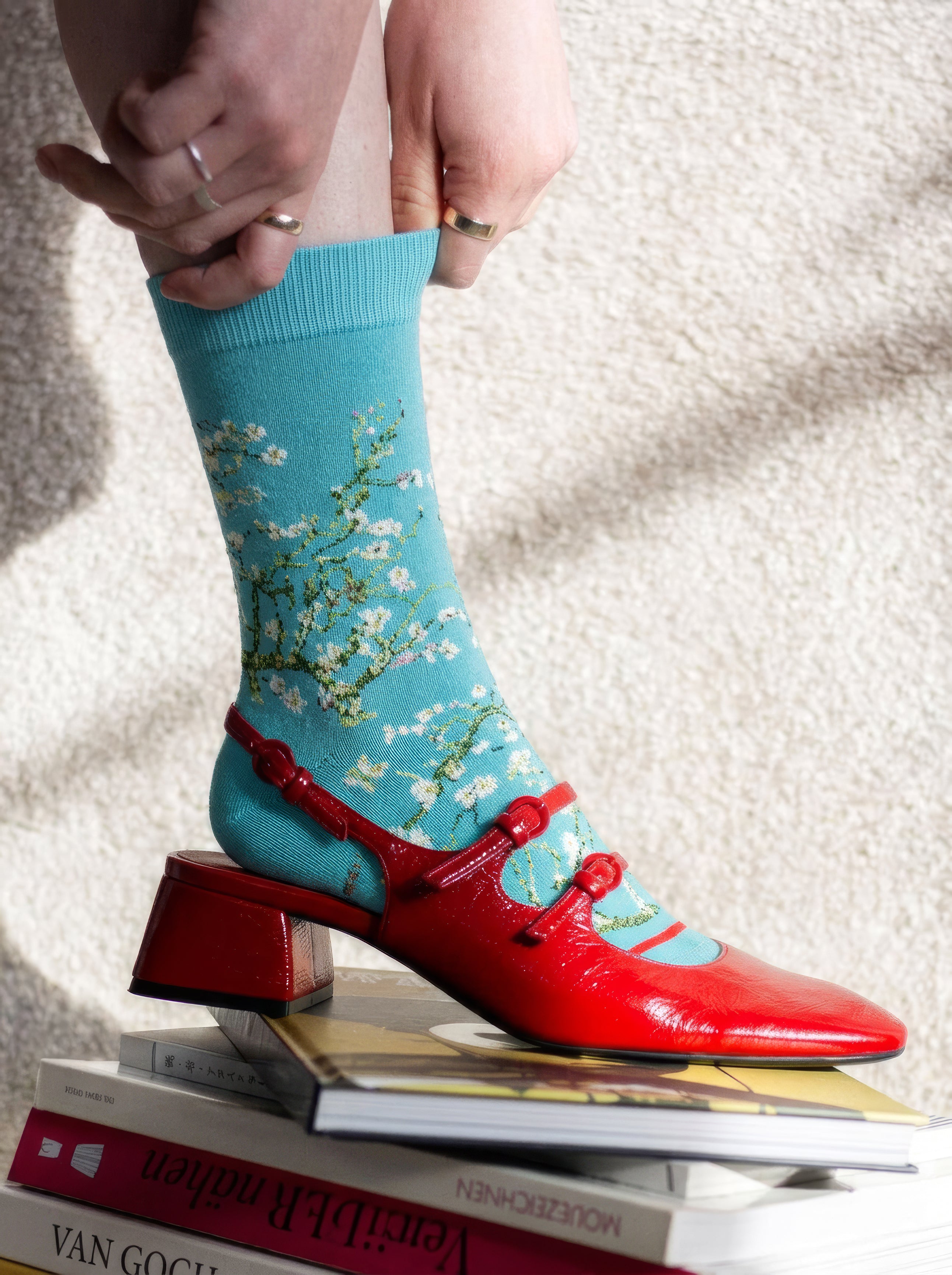 Van Gogh Almond Blossom art socks worn with red Mary Janes on stack of Van Gogh books – museum art gift from ArtyGifts
