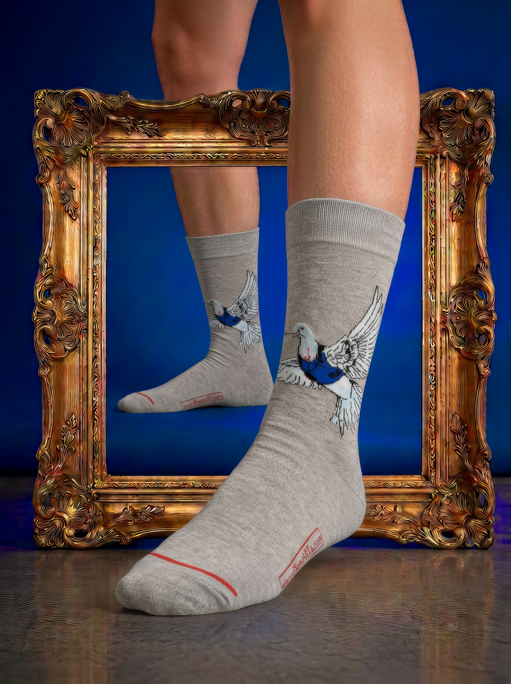 Grey Banksy-inspired Peace Dove art socks with a black and white dove motif, worn beside an ornate gold frame against a deep blue background.
