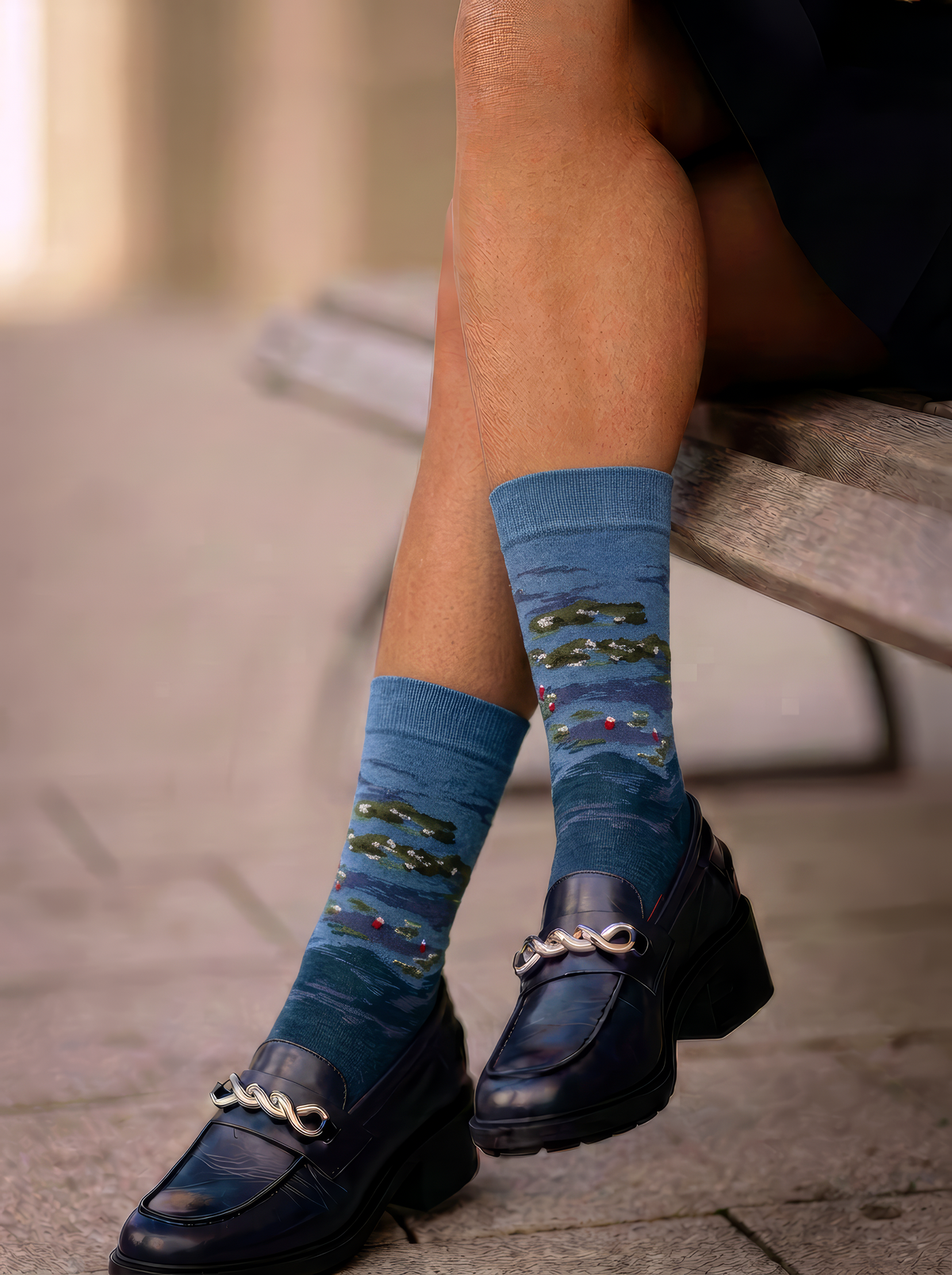 Person wearing blue XL crew socks featuring Claude Monet’s Water Lilies by Evening Light, styled with navy loafers with gold chain details.⠋

