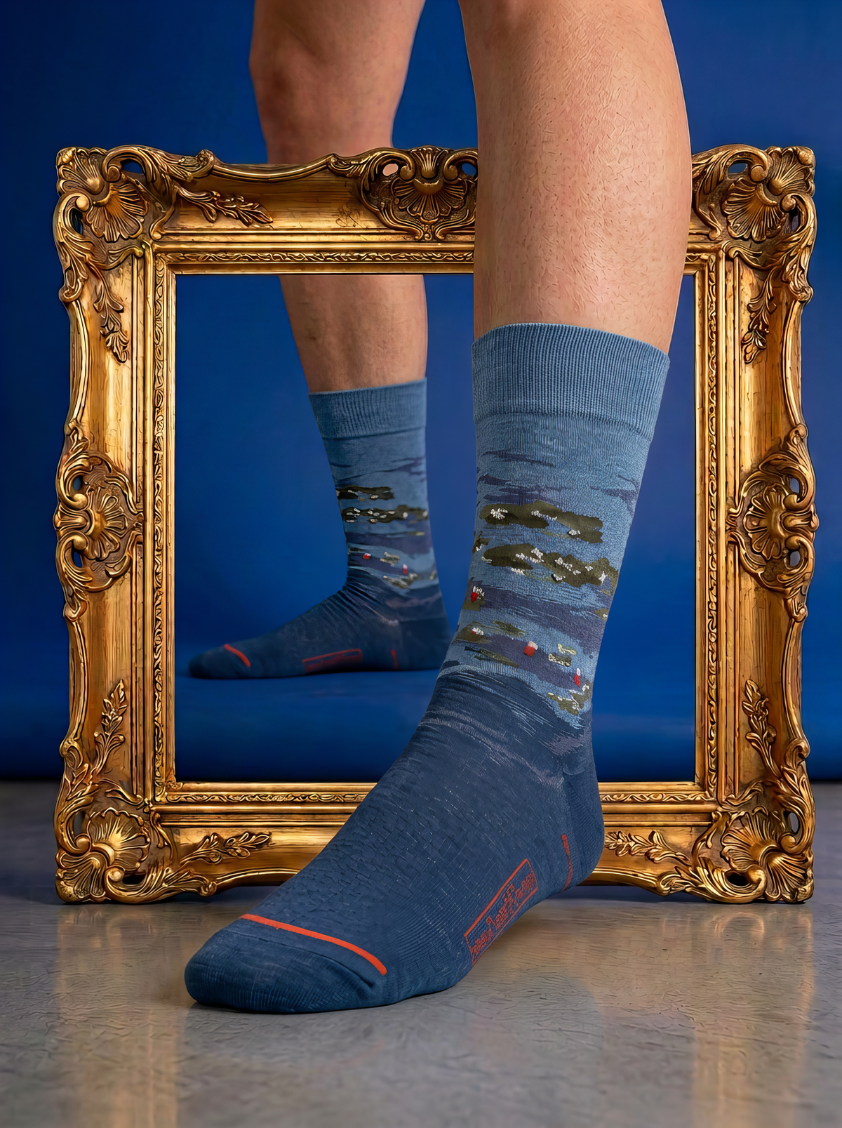 Pair of blue XL crew socks featuring Claude Monet’s Water Lilies by Evening Light, displayed through an ornate gold frame against a blue background.