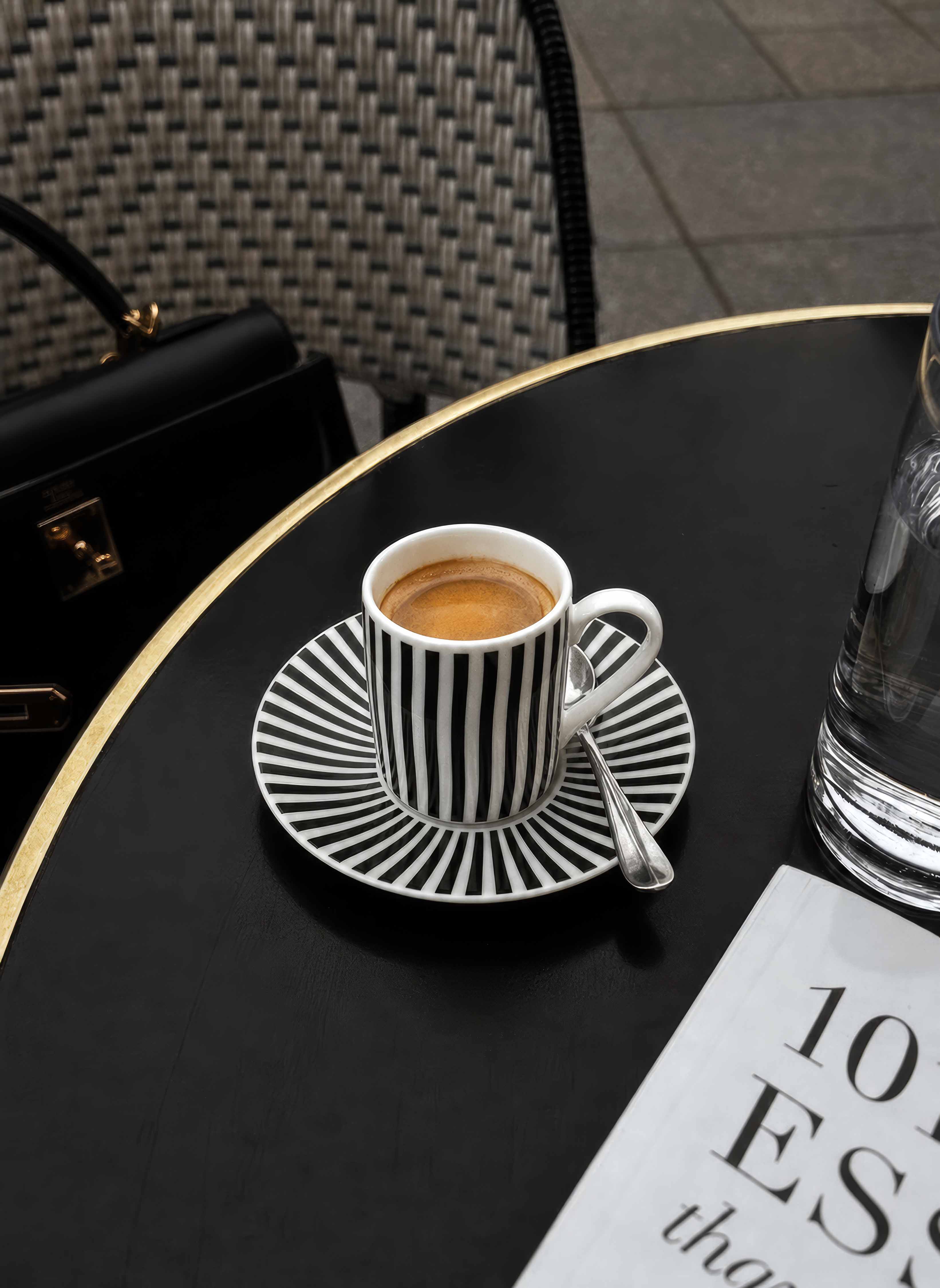 Optical Art espresso cup and saucer on dark table — bold black and white design by ArtyGifts
