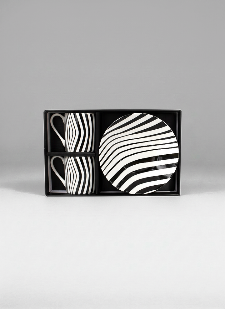 Set of black and white patterned ceramic items in a box on a gray background