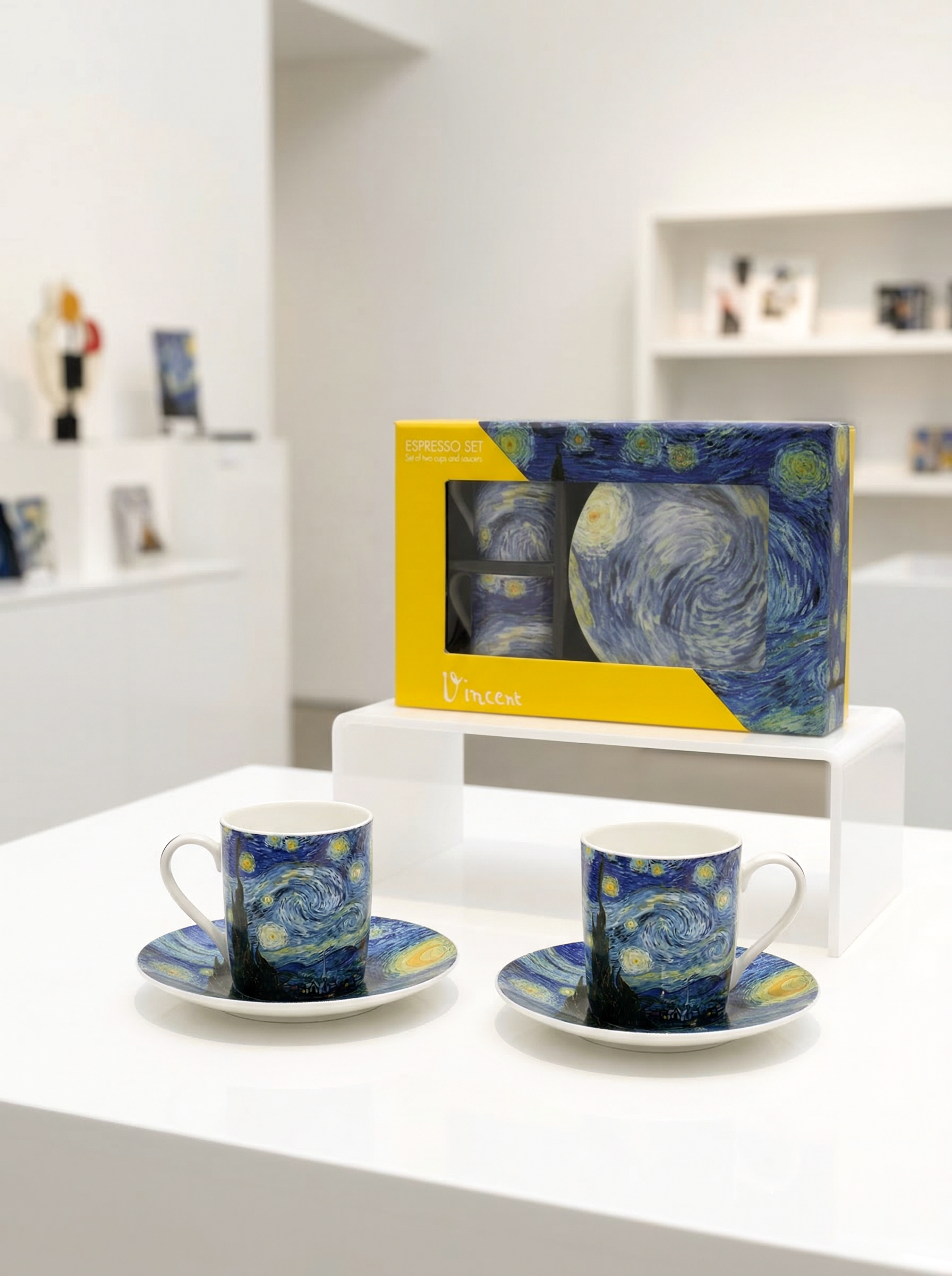 Two Van Gogh-themed coffee cups and saucers on a white surface with a box in the background.