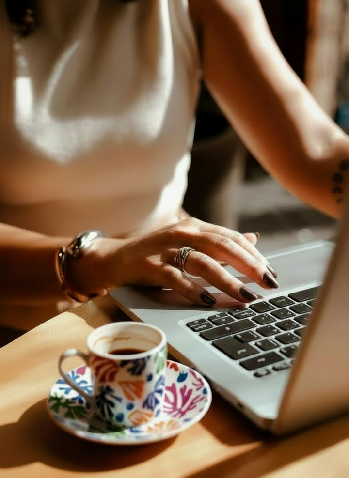Person using a laptop with a cup of coffee on a saucer I ArtyGifts