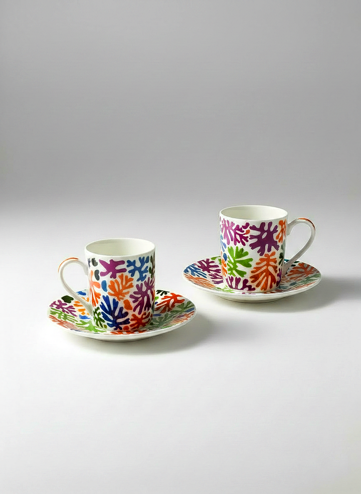 Two colorful ceramic cups and saucers on a light gray background