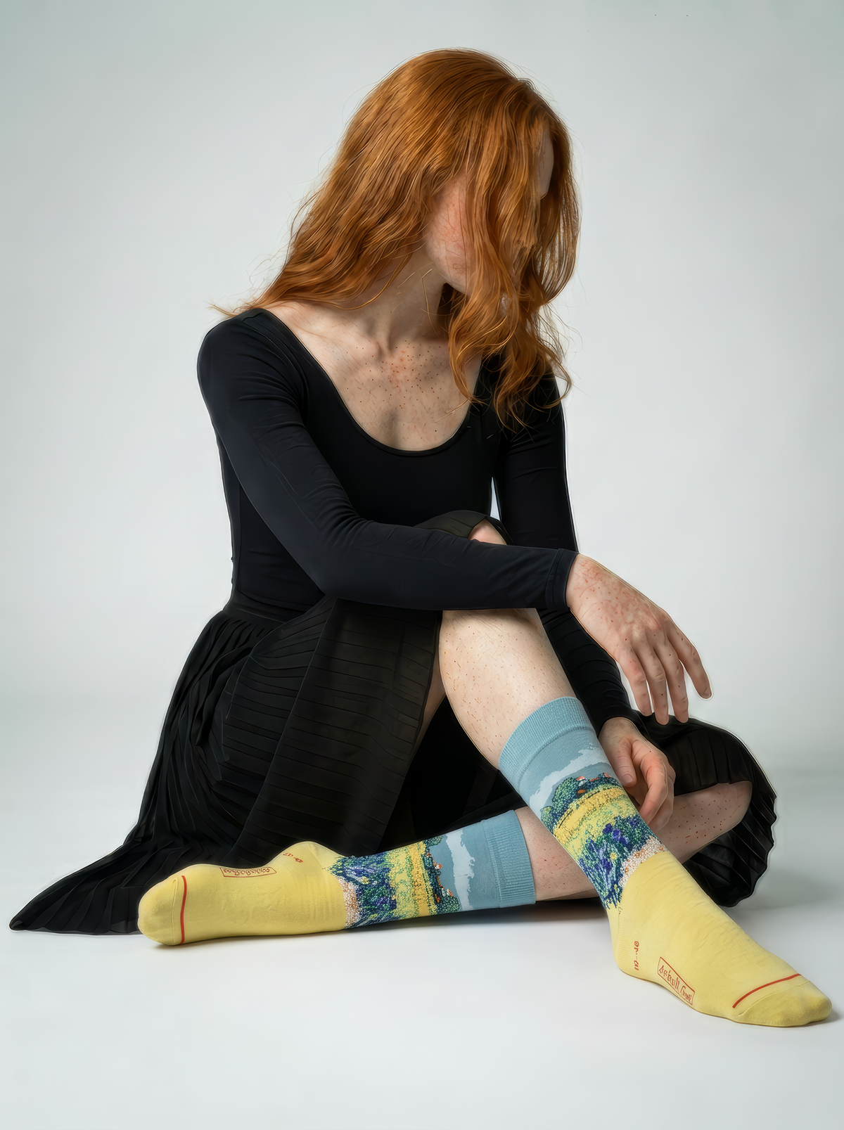 Person wearing yellow Field with Irises at Arles art socks while seated on the floor