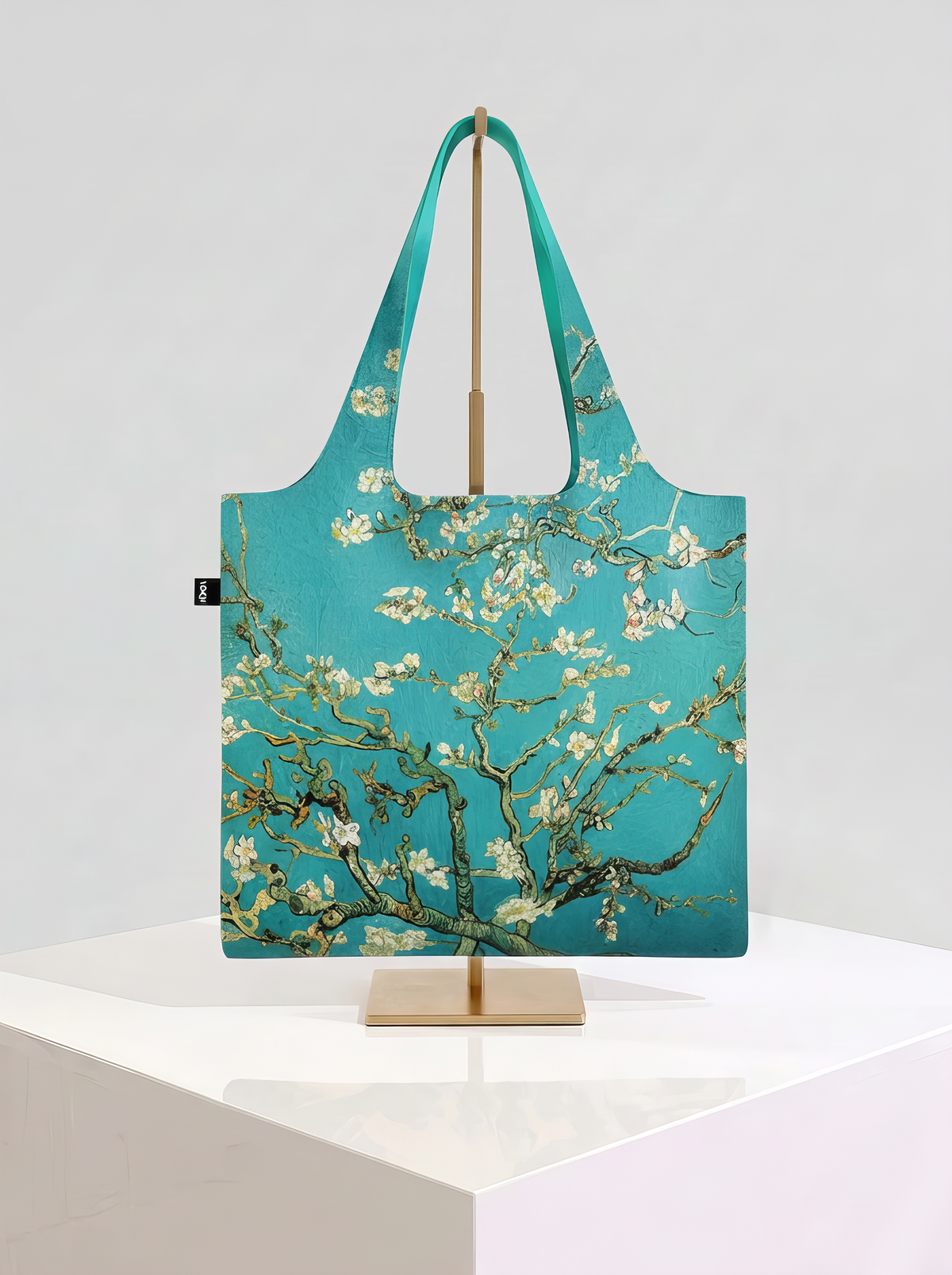 Foldable museum art shopper bag featuring Almond Blossom by Vincent van Gogh, displayed on a gold stand against a white museum-style background from ArtyGifts
