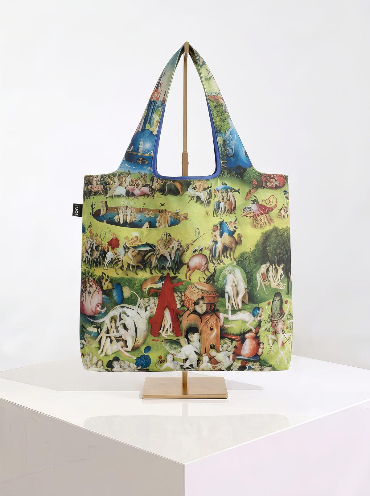 Foldable museum art shopper bag featuring Garden of Earthly Delights by Jheronimus Bosch, displayed on a gold stand against a white museum-style background from ArtyGifts
