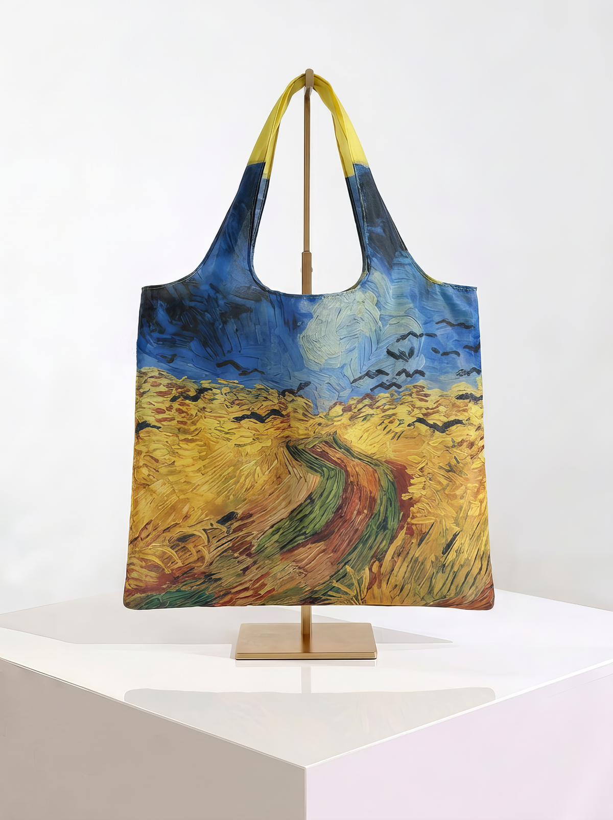 Foldable museum art shopper bag featuring Wheatfield with Crows by Vincent van Gogh, displayed on a gold stand against a white museum-style background from ArtyGifts
