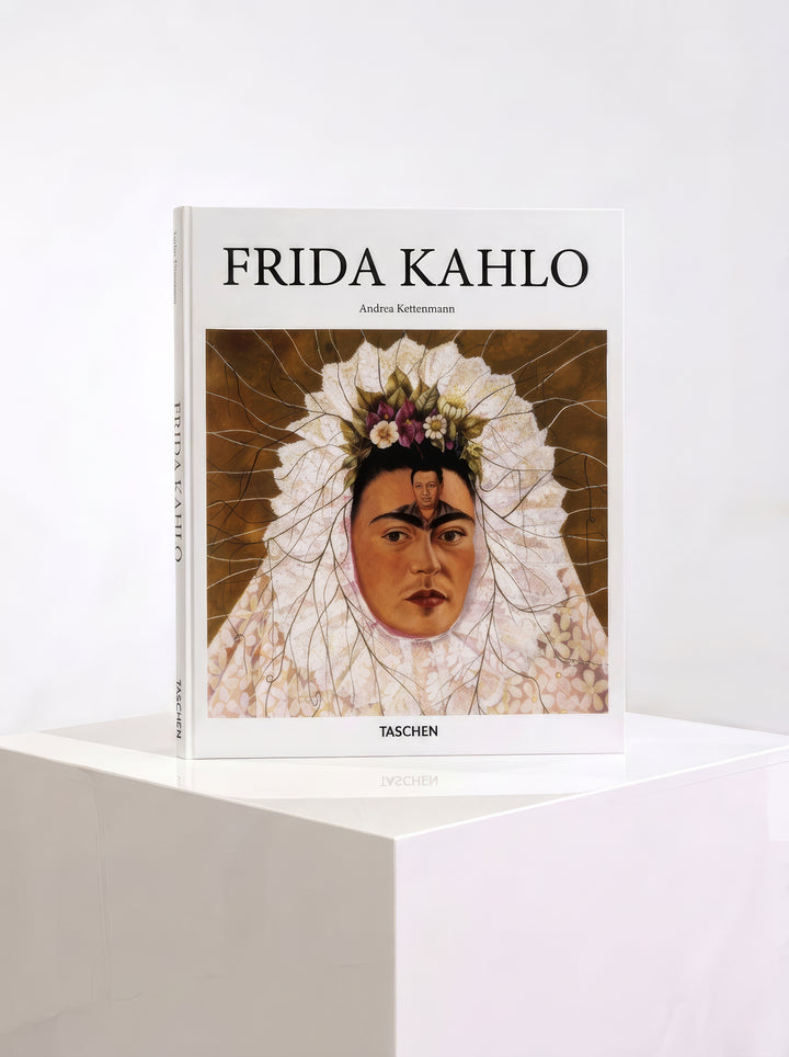TASCHEN Frida Kahlo hardcover art book by Andrea Kettenmann, featuring a self-portrait in a white Tehuana headdress on the cover, displayed on a white plinth.
