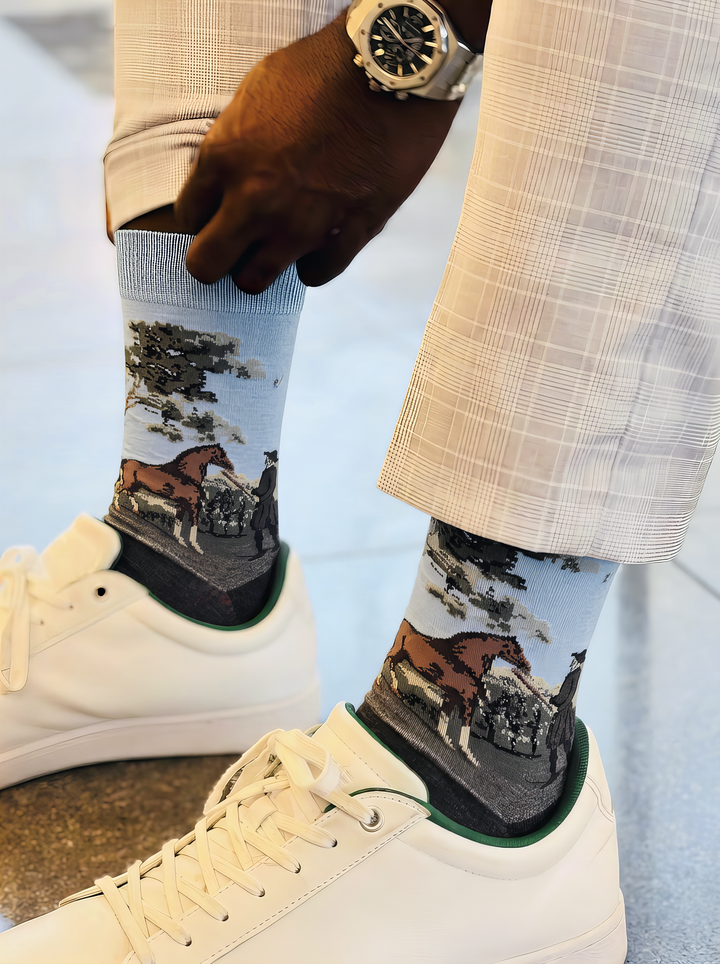 Close-up of charcoal grey ArtyGifts socks with pale blue cuffs, worn with light-coloured trousers and dark shoes.
