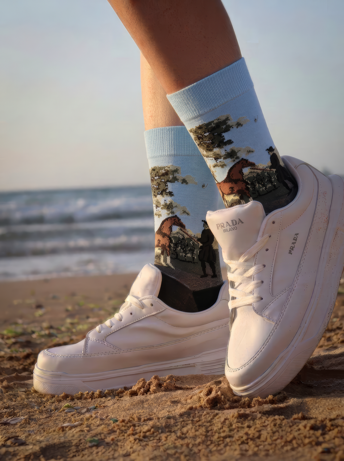 Person by the coast wearing charcoal grey ArtyGifts socks with pale blue cuffs and white sneakers.