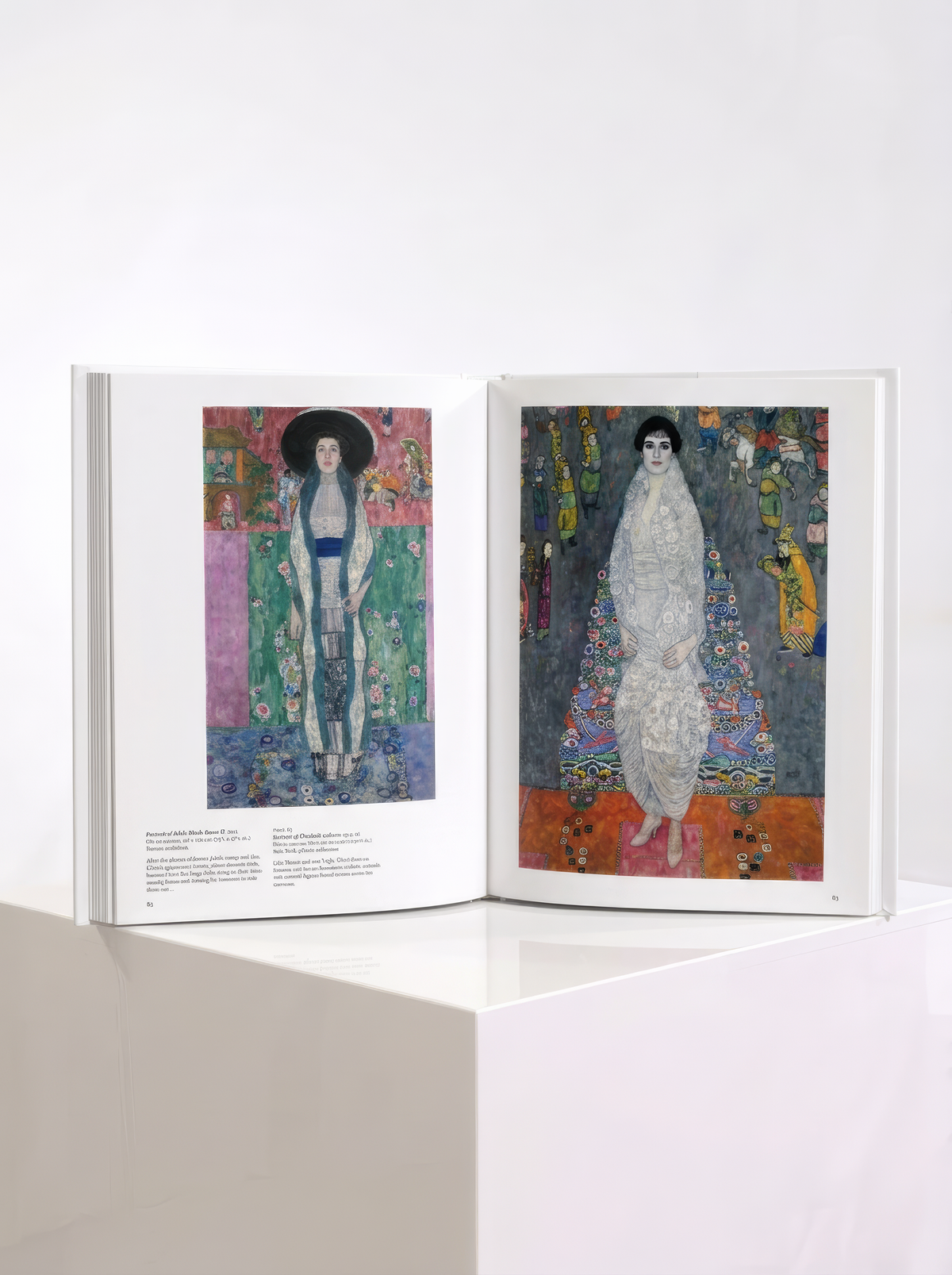 Open TASCHEN Klimt art book showing two full-length portraits of women against richly patterned backgrounds, displayed on a white plinth.
