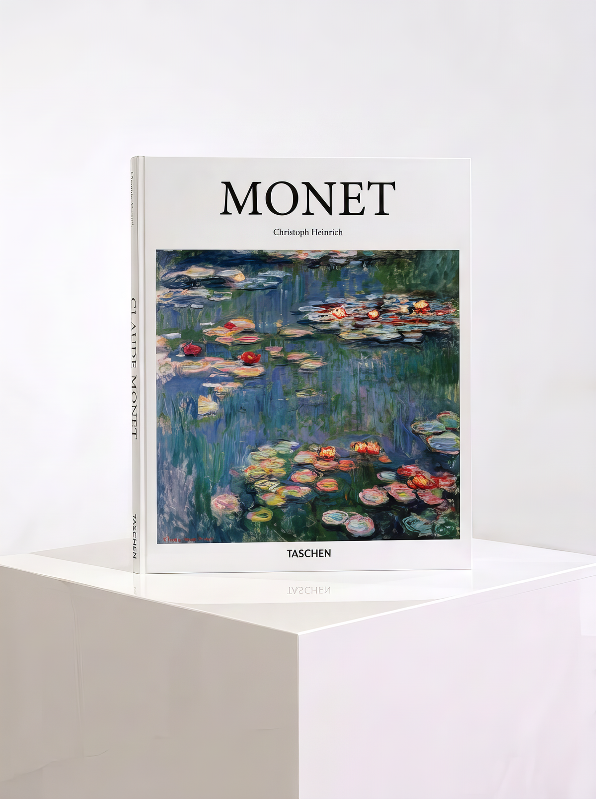 Monet hardcover art book by Christoph Heinrich, published by TASCHEN, with water lilies on the cover, displayed on a white plinth.

