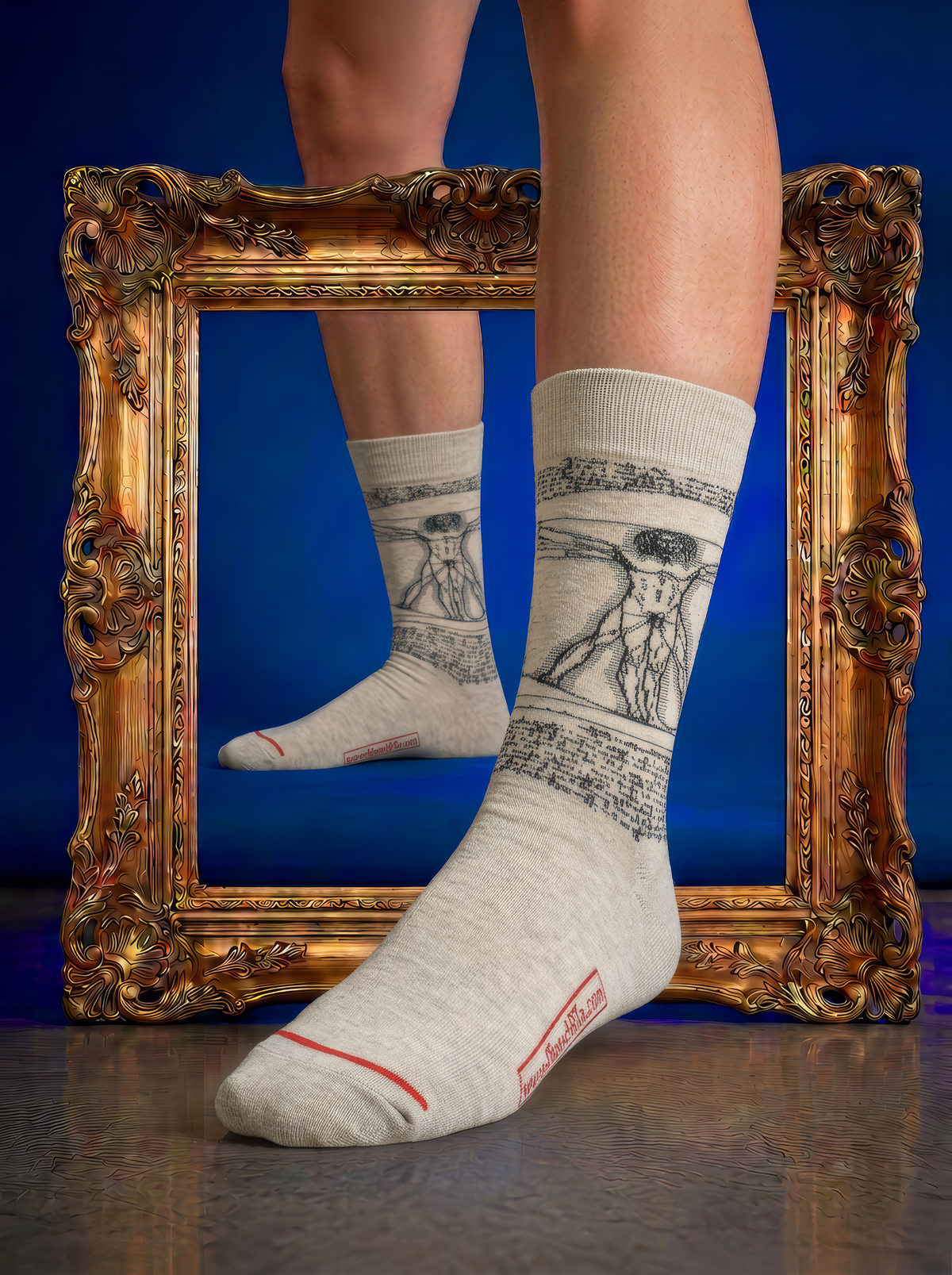 Cream socks with intricate black artwork, worn on feet beside an ornate gold frame against a deep blue background.
