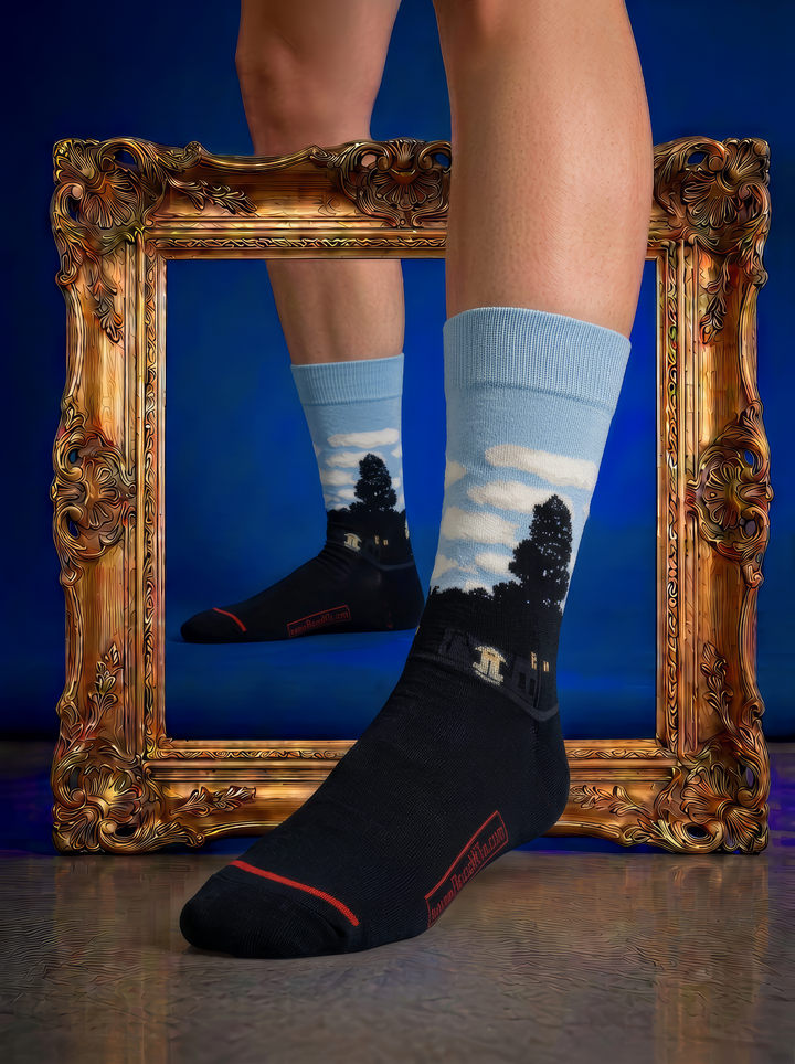Art socks with pale blue sky and dark silhouettes, worn on feet beside an ornate gold frame against a deep blue background.
