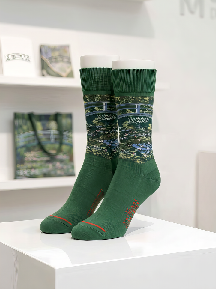 Officially licensed green Claude Monet The Japanese Bridge art socks for women and men, displayed on a white pedestal. A unique art gift for Monet lovers.