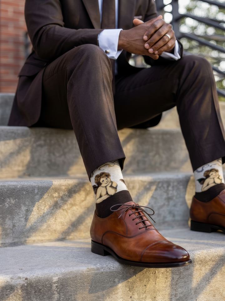 Sistine Madonna Angels art socks featuring Raphael’s artwork worn with brown leather lace-up shoes while seated outdoors