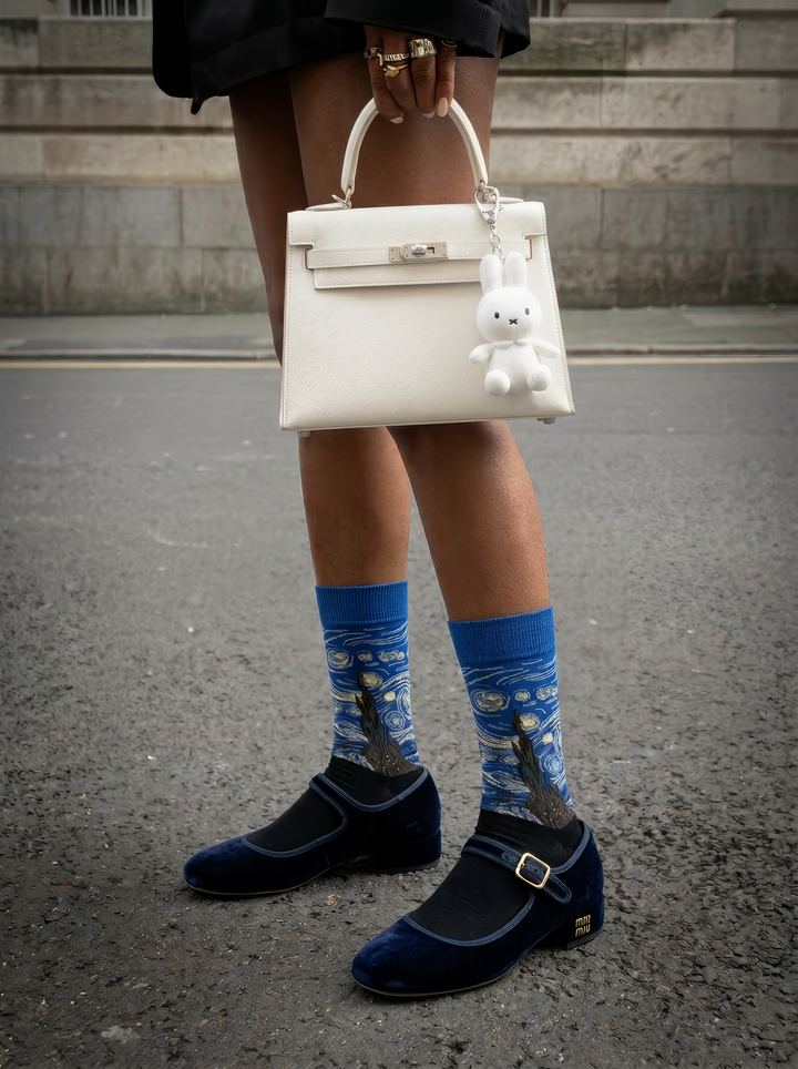 Starry Night Classic art socks by Vincent van Gogh worn with navy Mary Jane shoes and a white handbag on a city street⠋

