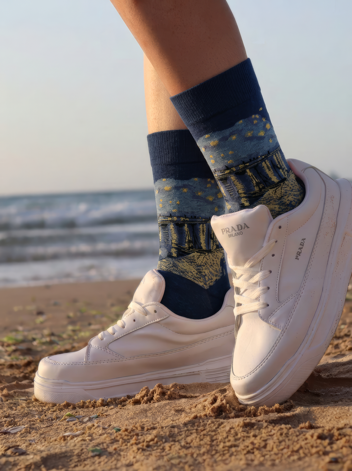 Starry Night over the Rhône art socks worn with white sneakers beside a coastal landscape