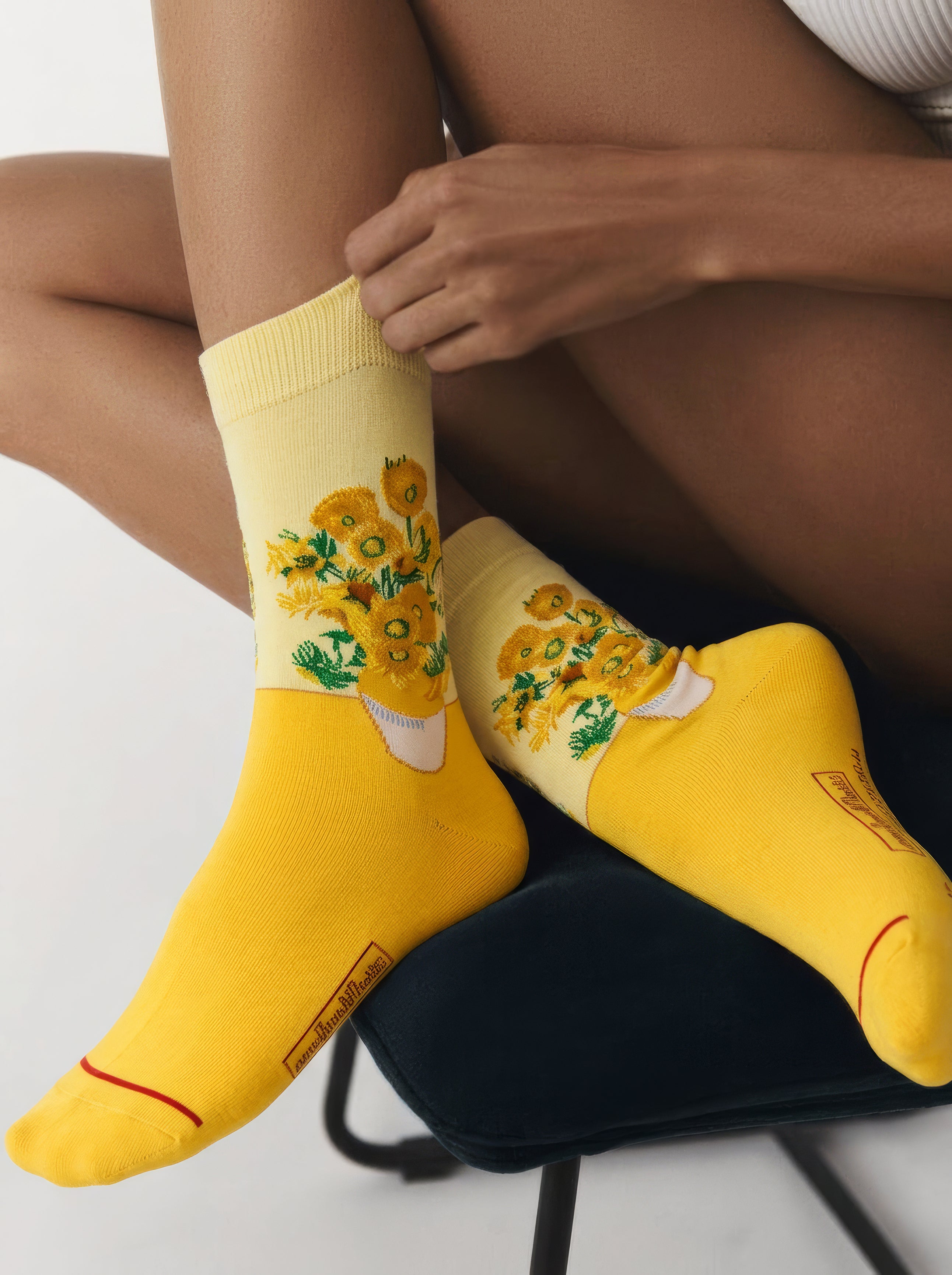Vincent van Gogh Sunflowers art socks worn by woman pulling up sock while seated – museum art gift from ArtyGifts
