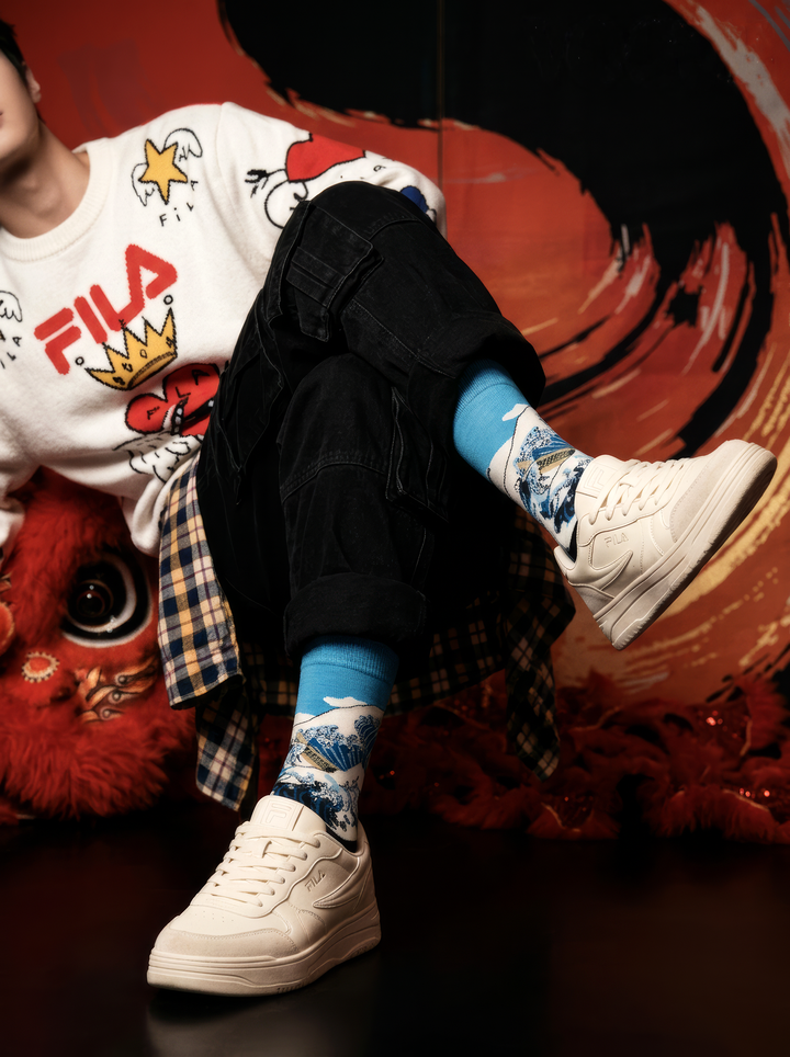 The Great Wave Blue art socks by Katsushika Hokusai styled with black shoes against a red and orange background