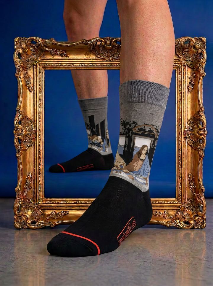 The Last Supper art socks featuring Leonardo da Vinci’s artwork worn with a black leather loafer in front of a gold frame