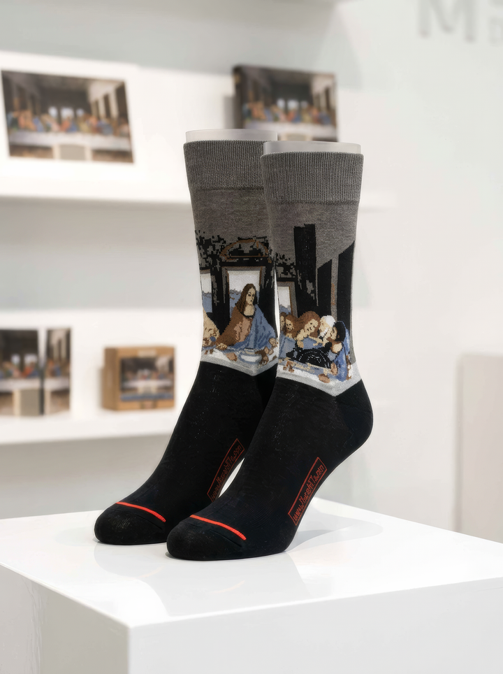 Black and grey The Last Supper art socks featuring Leonardo da Vinci’s artwork displayed on a white pedestal