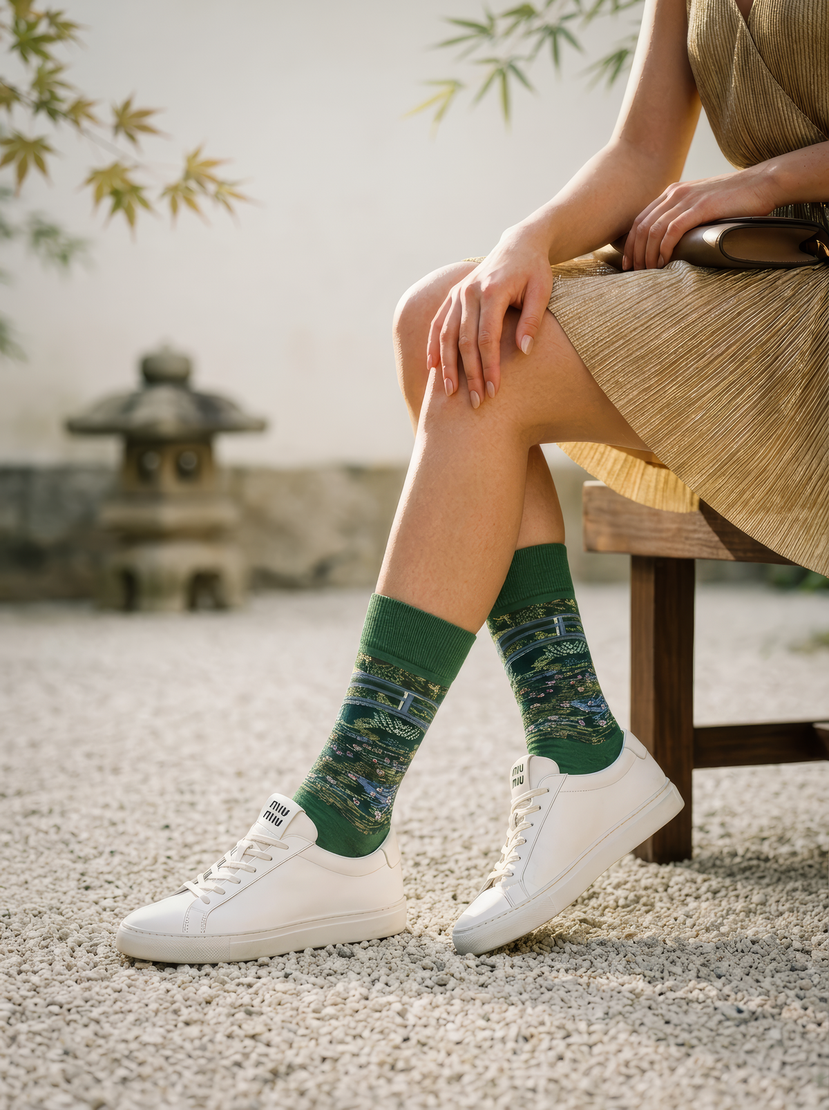 Person wearing green Claude Monet The Japanese Bridge art socks with a beige outfit and white sneakers while seated outdoors. For women and men.