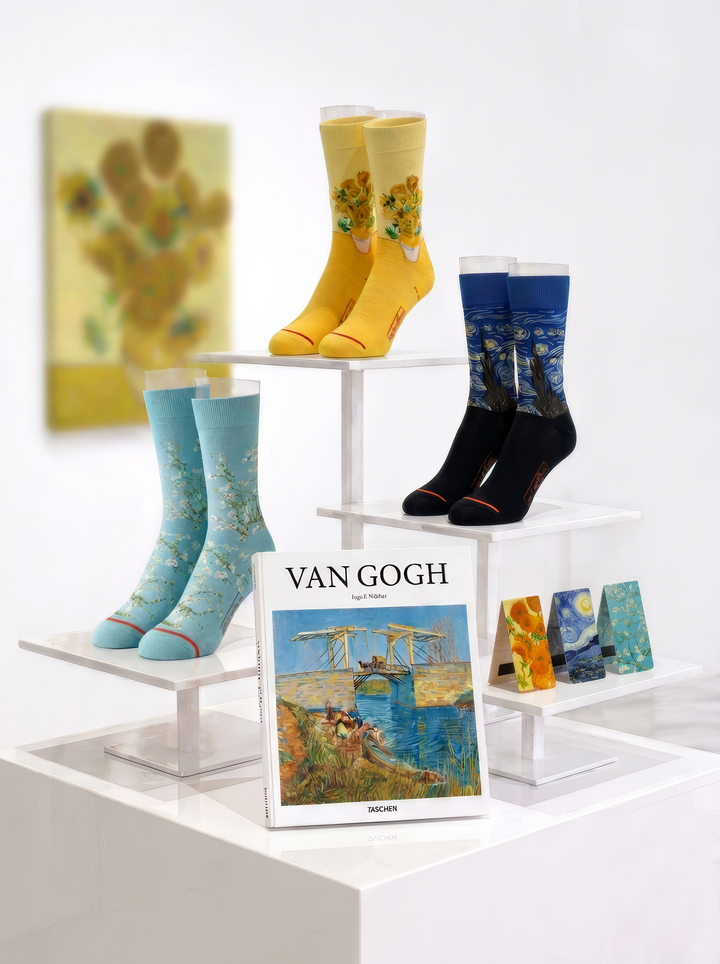 Van Gogh gift set featuring museum art socks with masterpiece prints, a Van Gogh art book and a matching bookmark set, arranged on white display stands.⠋

