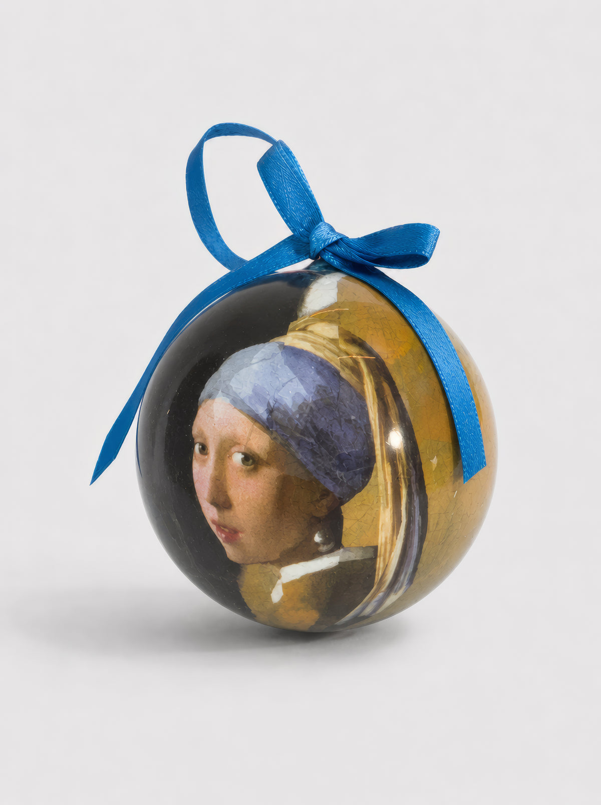 Close-up of a Johannes Vermeer Girl with a Pearl Earring Christmas bauble with blue ribbon on a light grey background – officially licensed museum art ornament, 7 cm diameter, unbreakable, in gift box. A unique Dutch Golden Age art Christmas gift from ArtyGifts.


