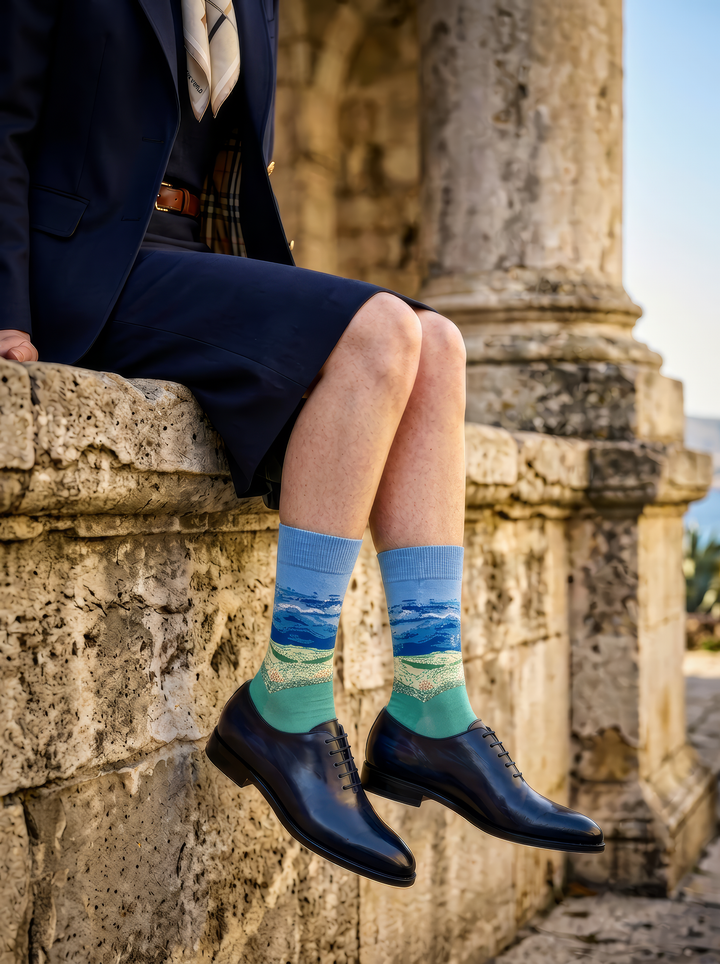 Wheat Field under Thunderstorm Sky unisex art socks by Vincent van Gogh worn with navy leather lace-up shoes beside historic stone architecture⠋

