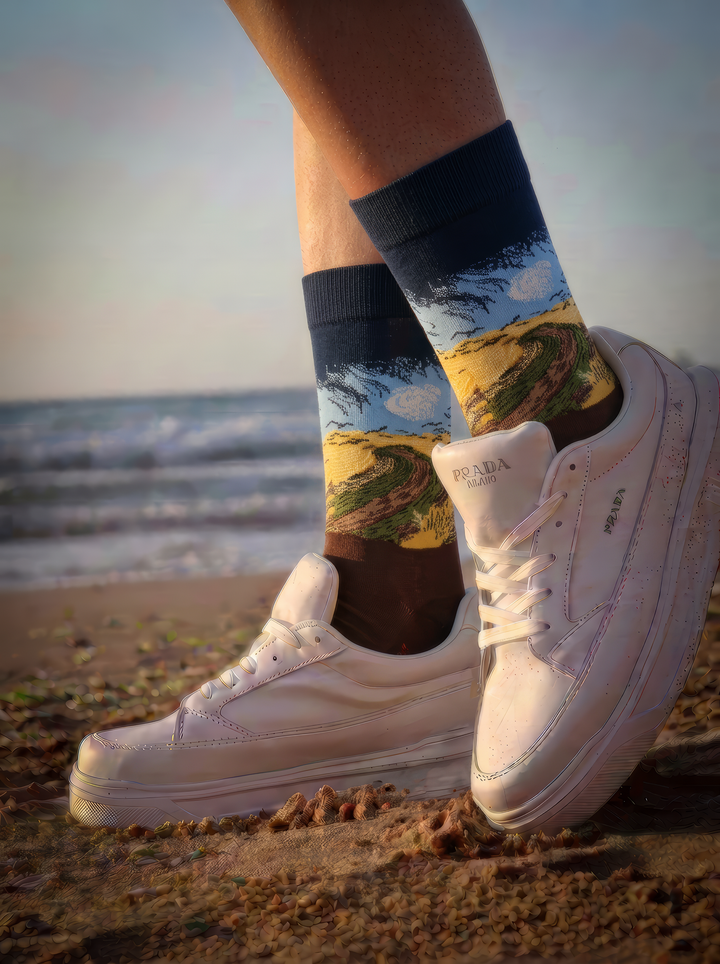 Wheatfield with Crows art socks by Vincent van Gogh worn with white sneakers on a sandy beach