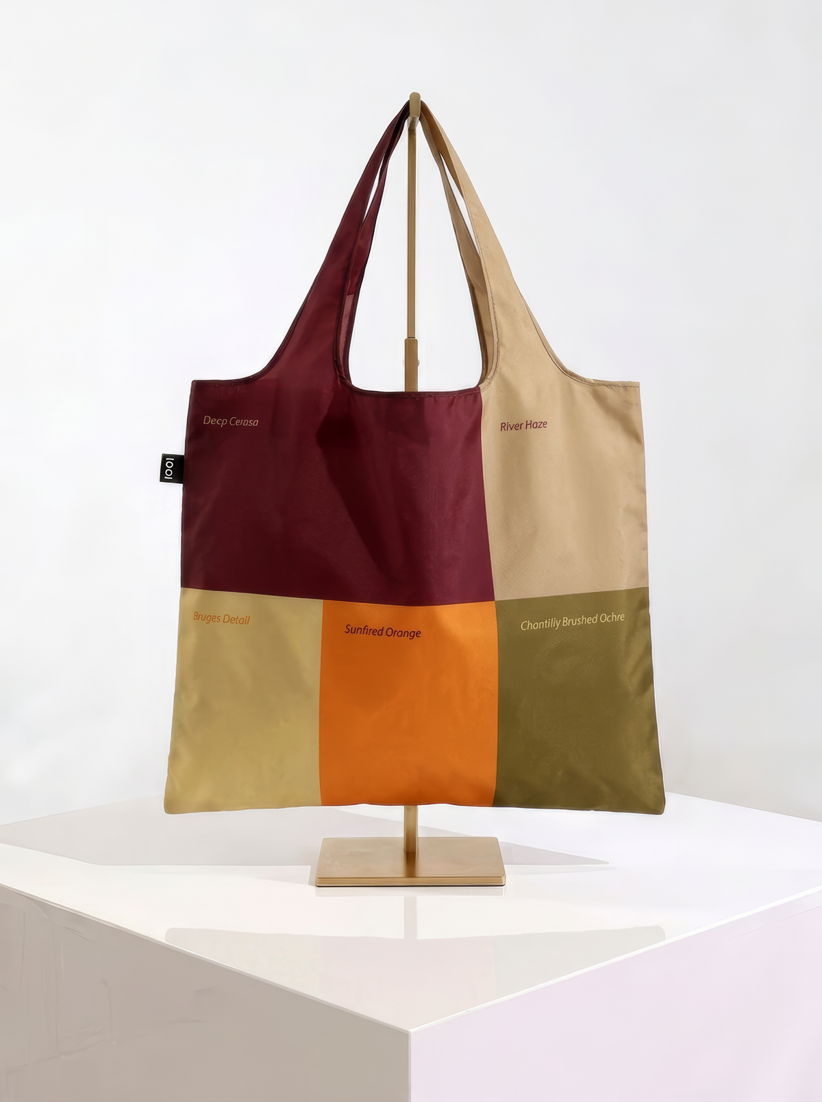 Reverse of the Whistlejacket shopper bag, showing burgundy, cream, ochre and olive colour blocks, displayed on a stand.
