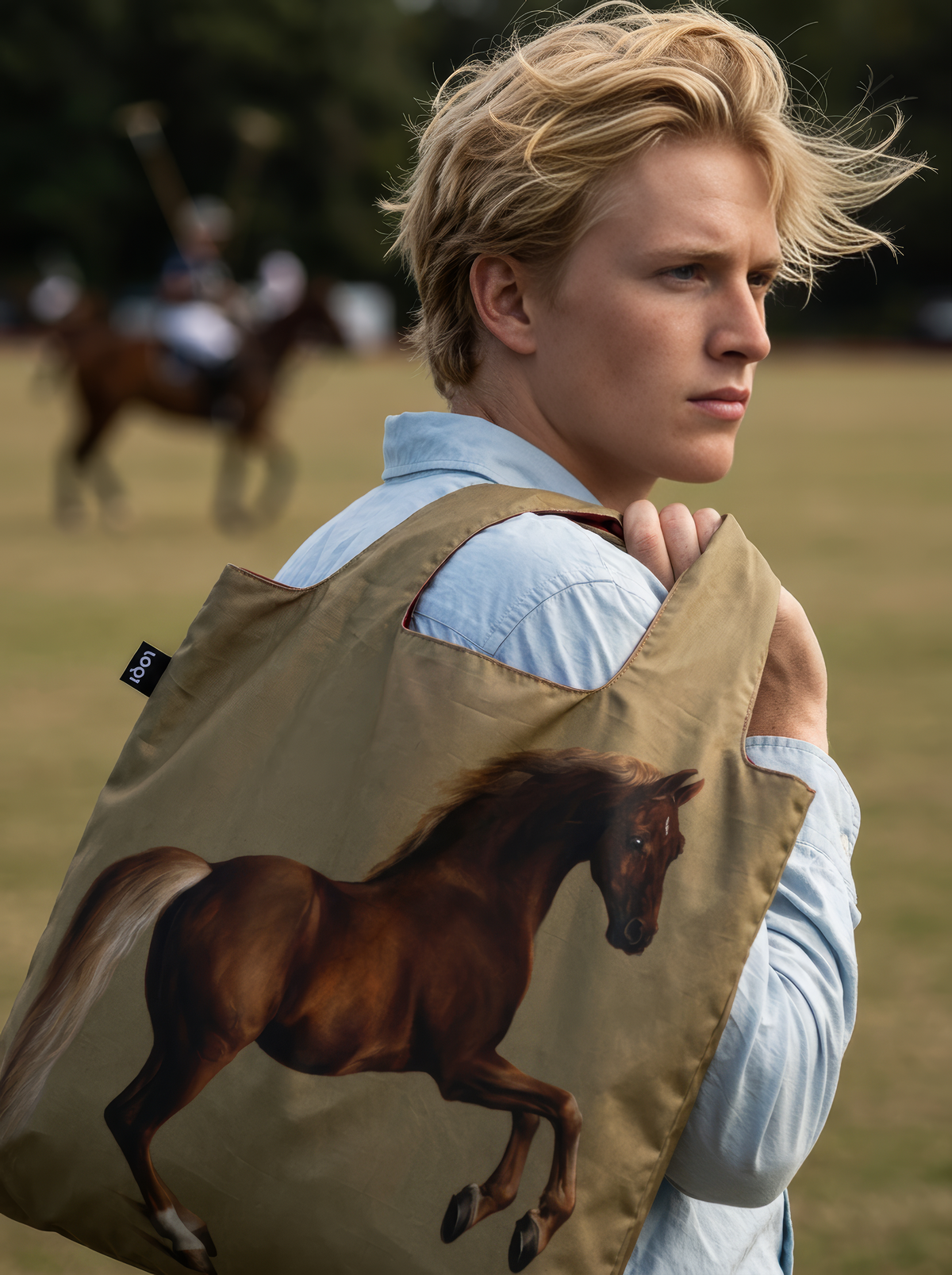 Close-up of a man carrying the Whistlejacket shopper bag over his shoulder, with the horse artwork visible against a grassy countryside backdrop.

