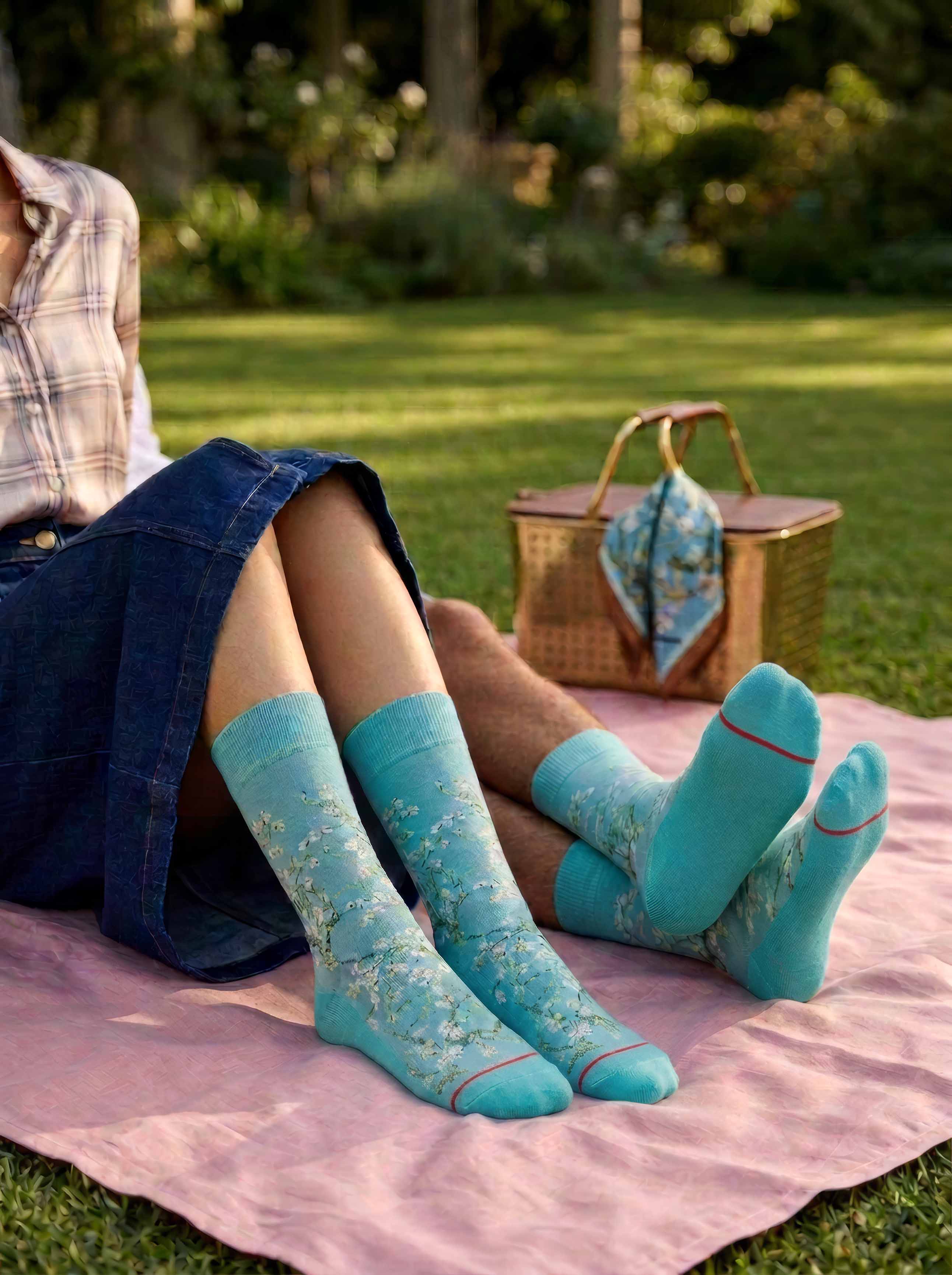 Man and woman wearing Van Gogh Almond Blossom art socks relaxing outdoors on a picnic blanket — unisex art gift ArtyGifts