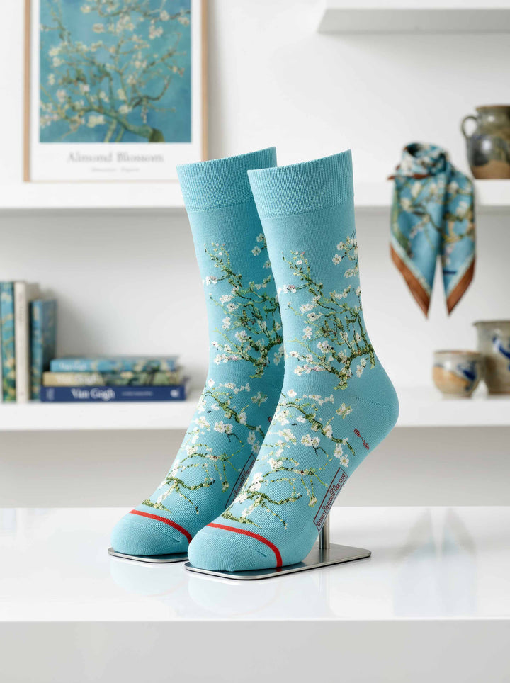 Van Gogh Almond Blossom art socks on display stand, with Almond Blossom painting and scarf in background — ArtyGifts