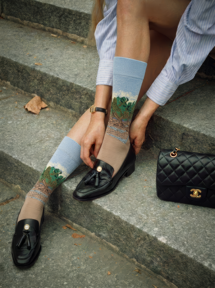 The Olive Trees art socks by Vincent van Gogh worn with black loafers while seated on stone steps