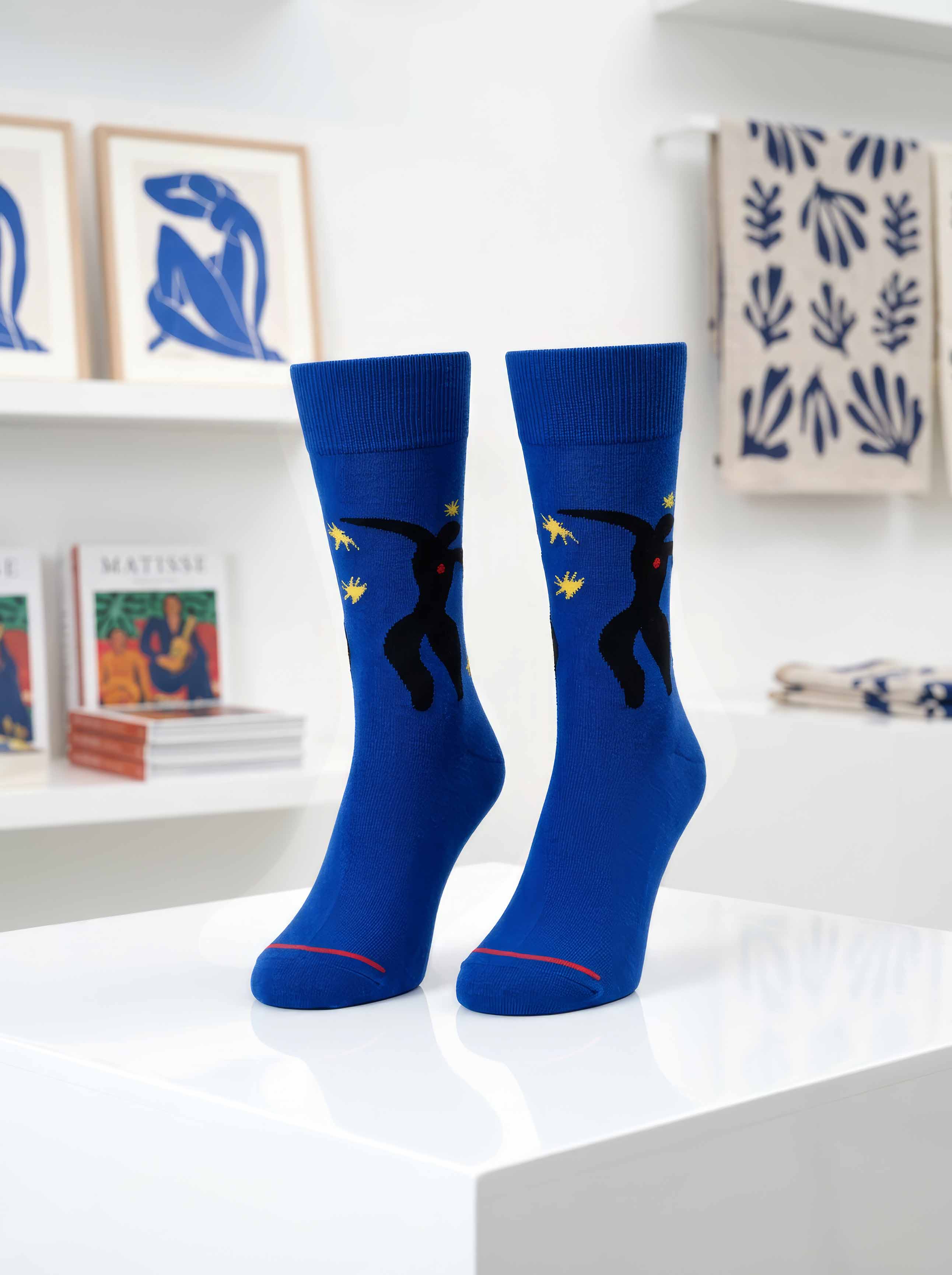 Matisse Icarus art socks on display in museum setting with Henri Matisse artworks in background — ArtyGifts