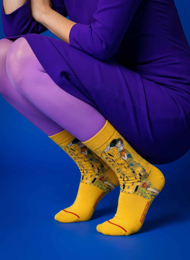 Woman in purple outfit wearing MuseARTa Klimt The Kiss art socks — unisex Art Nouveau museum gift ArtyGifts

