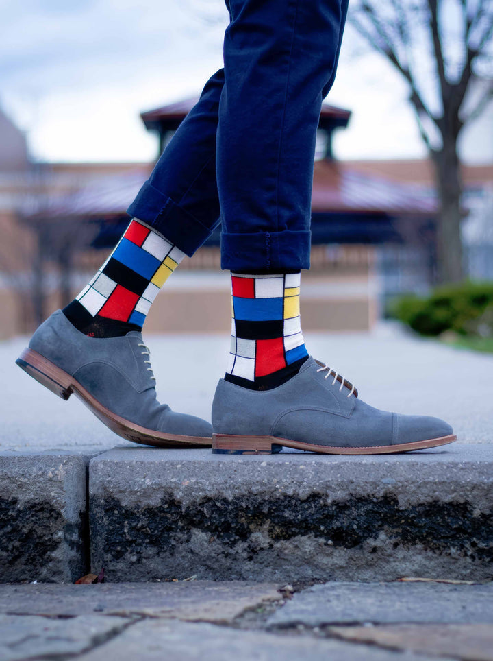 Man wearing MuseARTa Mondrian art socks with grey Oxford shoes on outdoor steps — classic art gift ArtyGifts