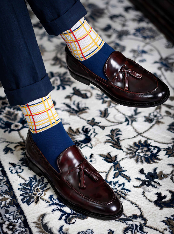 Man wearing MuseARTa Mondrian New York City art socks with brown Oxford shoes on floral background — elegant De Stijl gift ArtyGifts
