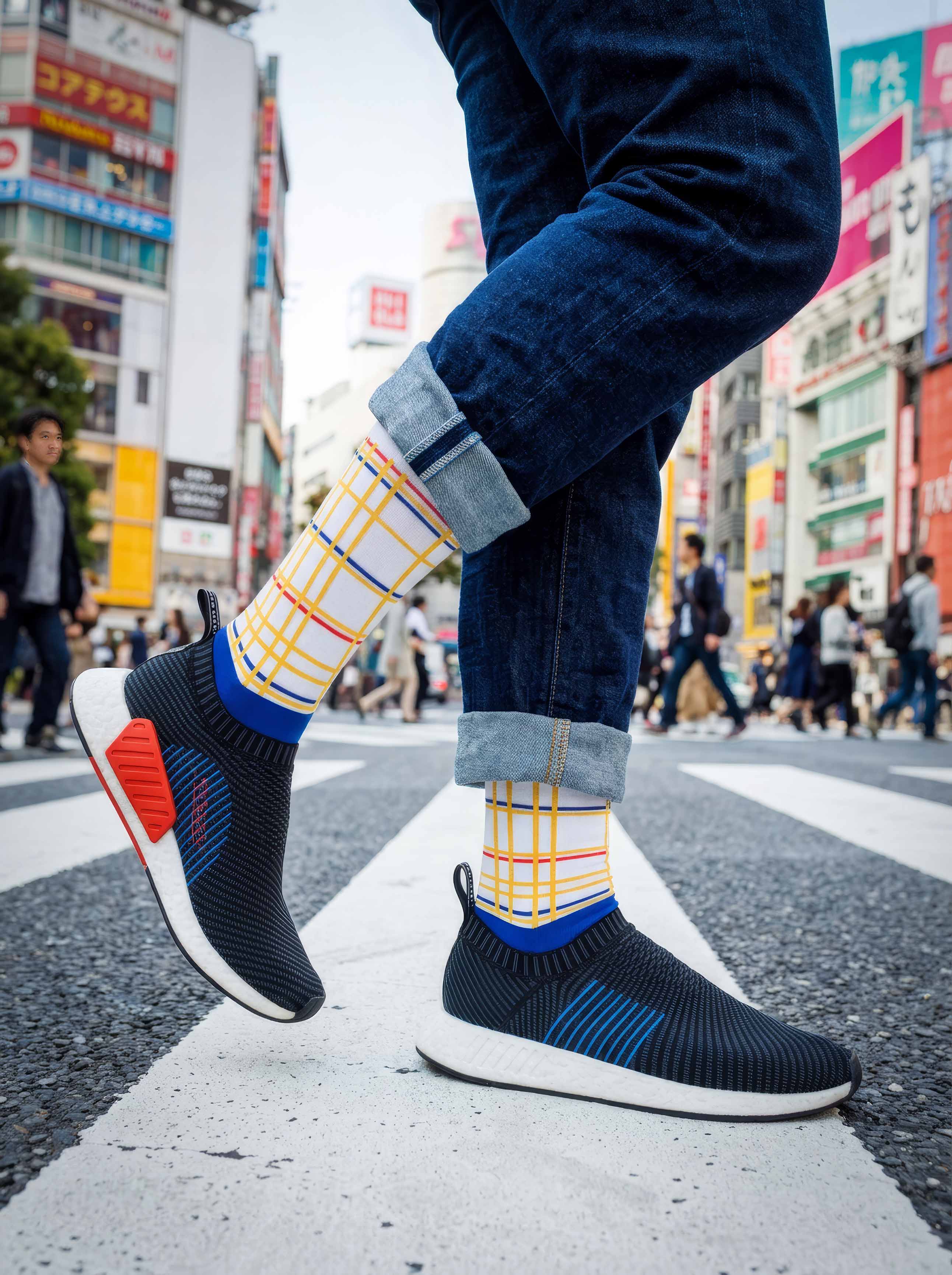Man wearing MuseARTa Mondrian New York City art socks on Tokyo street with blue sneakers — urban De Stijl street style gift ArtyGifts

