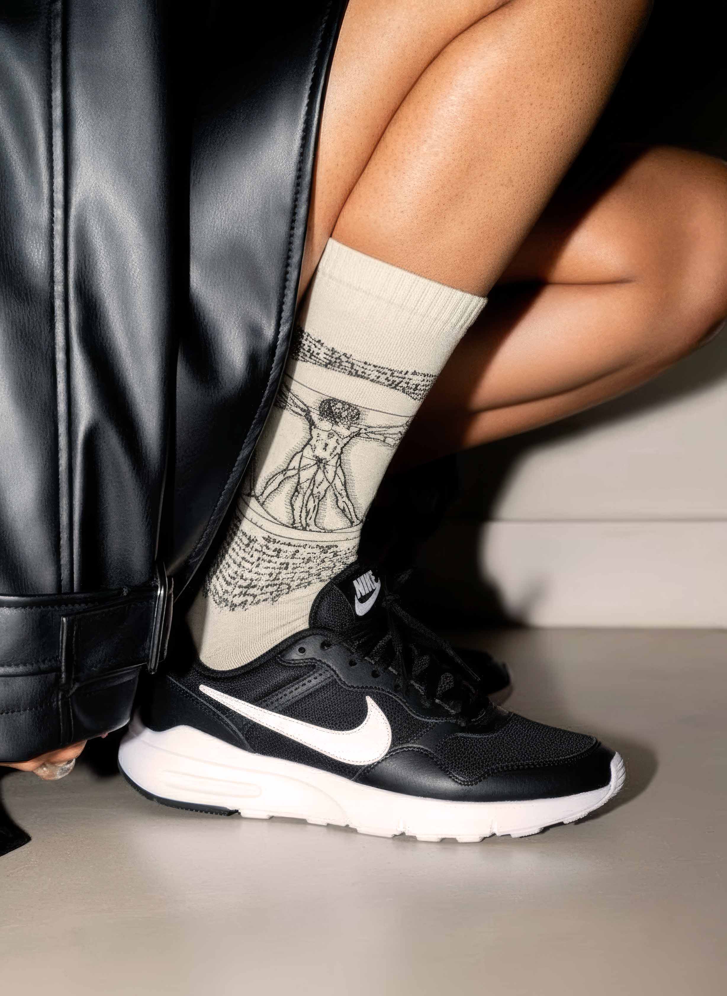 Woman wearing Da Vinci Vitruvian Man art socks with white Nike sneakers — unisex art gift ArtyGifts